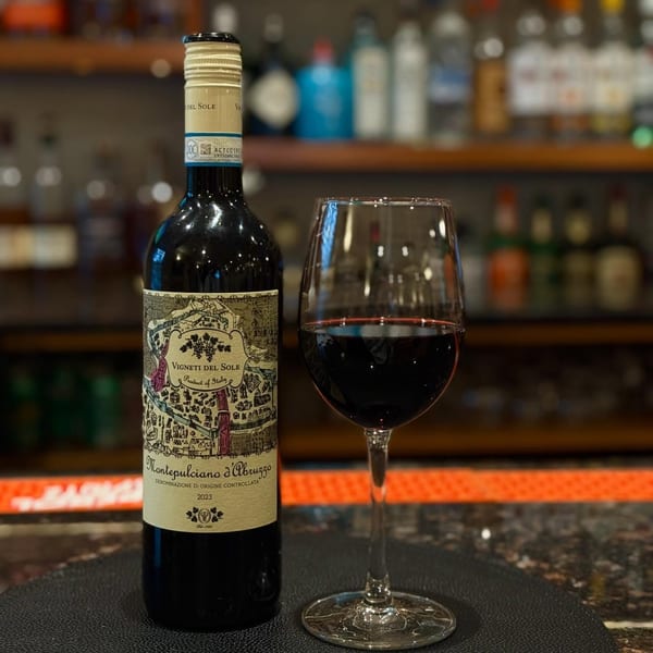 A bottle of Vigneti del Sole Montepulciano d'Abruzzo wine next to a glass of red wine at a bar.